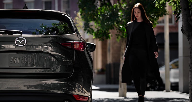 Woman walking on sidewalk next to a 2020 Mazda CX-5 | Russell & Smith Mazda in Houston, TX